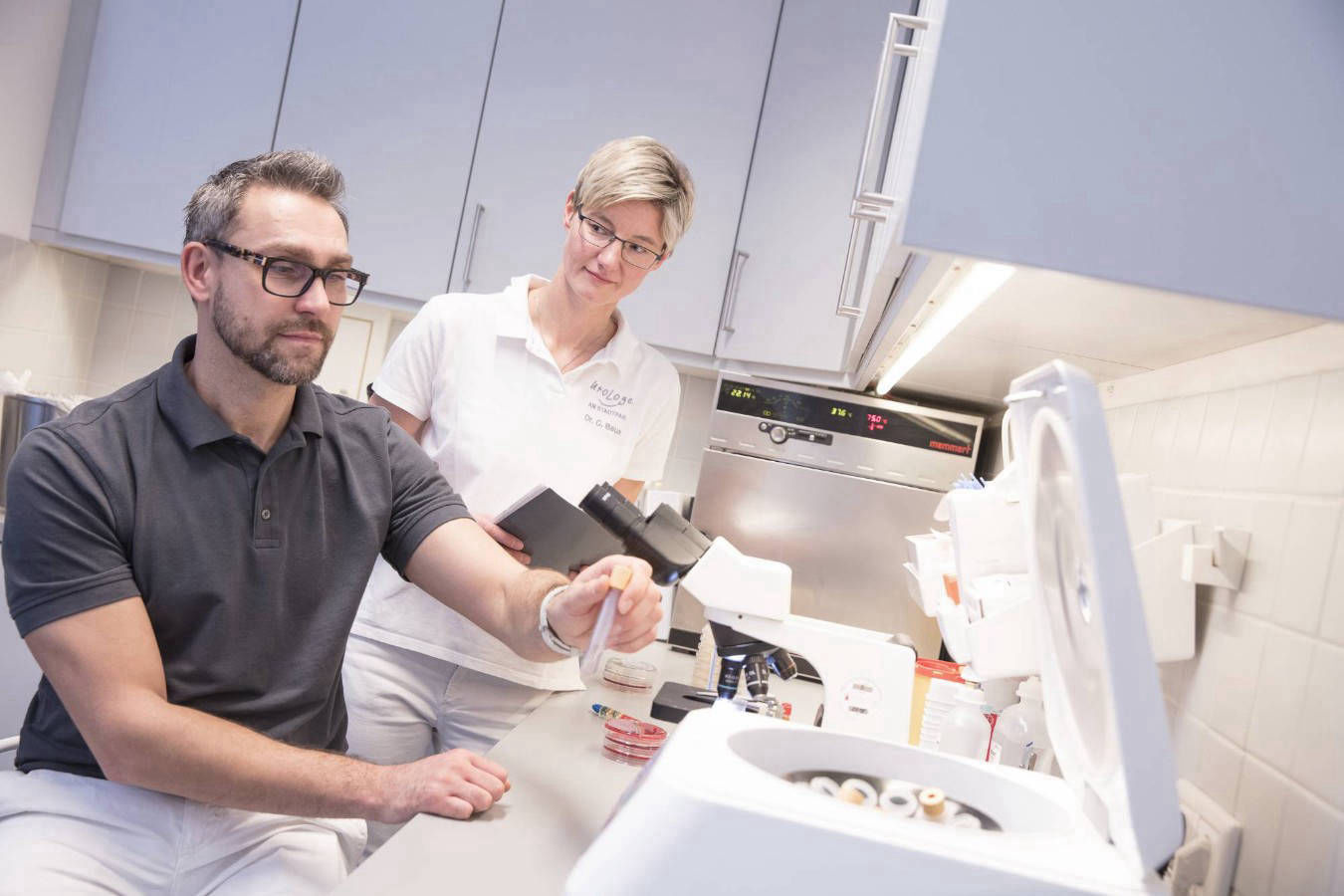 Ärztin mit Laborant an Messgeräten arbeitend